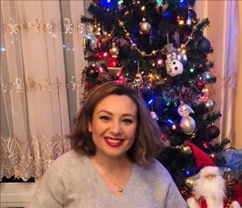 female employee posing in front of Christmas tree