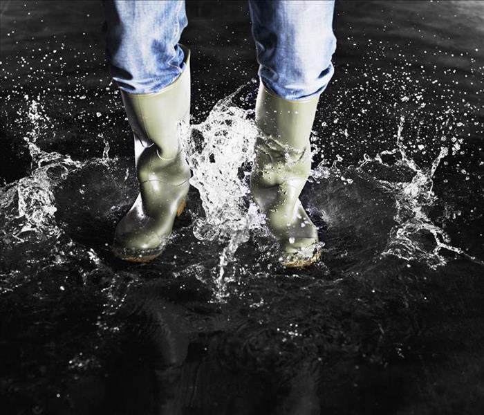 boots splashing in water with person wearing blue jeans